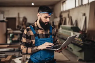 Focused professional carpenter looks at his laptop