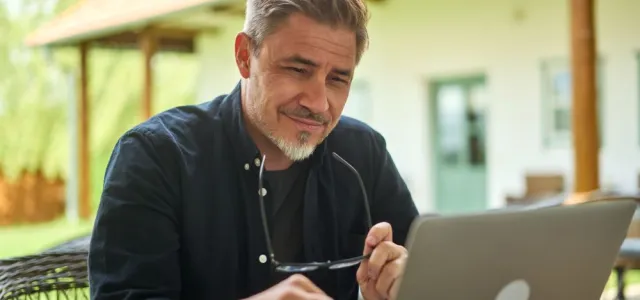 Middle aged man working with laptop computer at home outdoor in garden