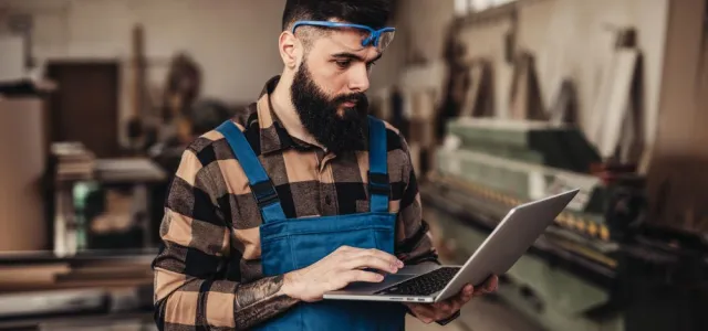 Focused professional carpenter looks at his laptop